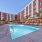 West Sacramento, CA Luxury Studio Apartments | The Bernice | Pool with Spacious Sun Deck, Lounge Chairs, Umbrellas, and Palm Trees.
